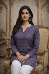 Woman in a patterned purple top sitting on an ornate chair with a decorative background