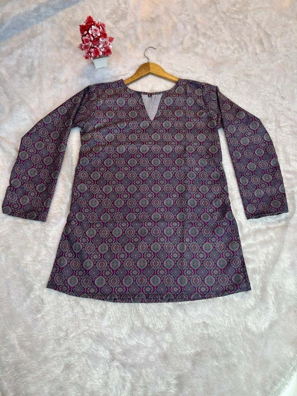 Purple patterned top on a hanger against a light background
