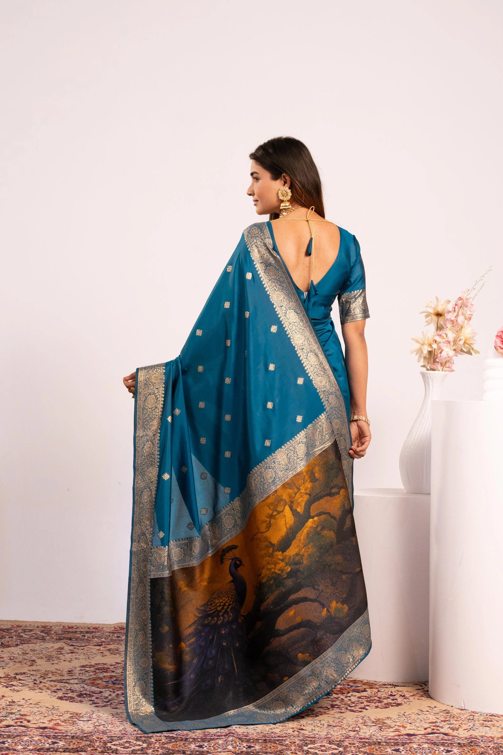 Woman wearing a blue saree with a peacock design on a white background