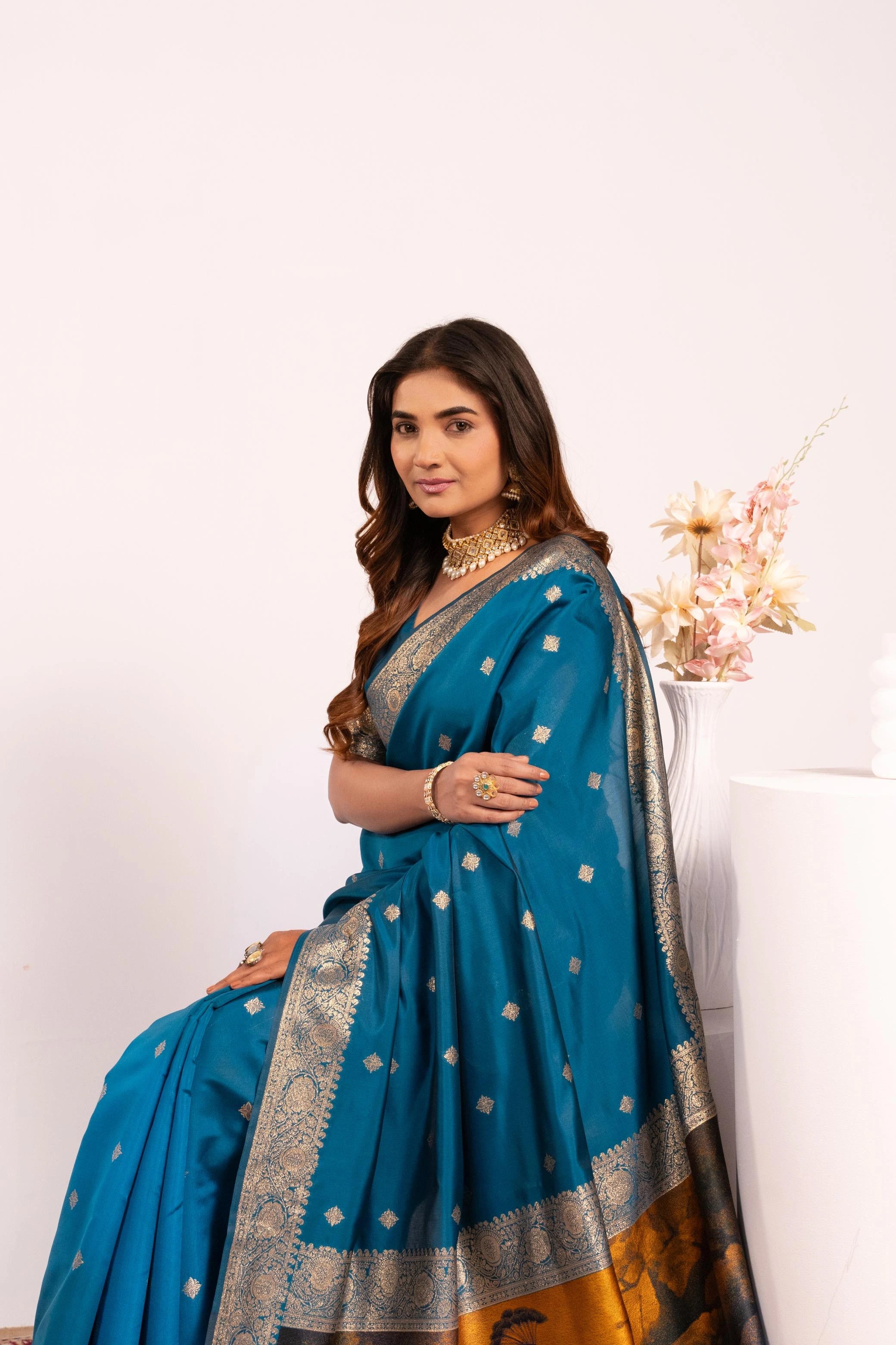 Woman wearing a blue saree with gold patterns on a white background