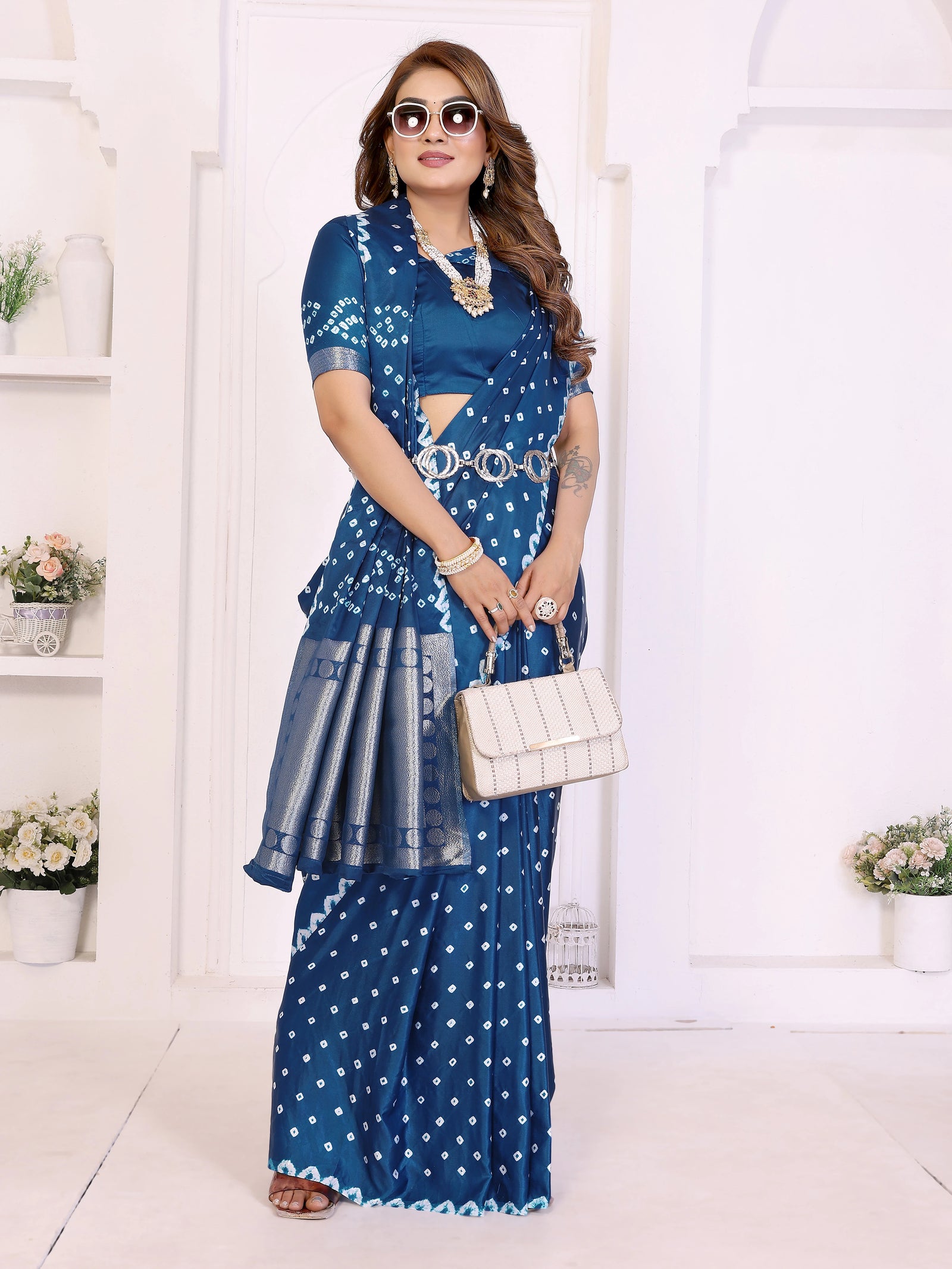 Woman wearing a blue patterned outfit with a white handbag in a minimalistic setting.