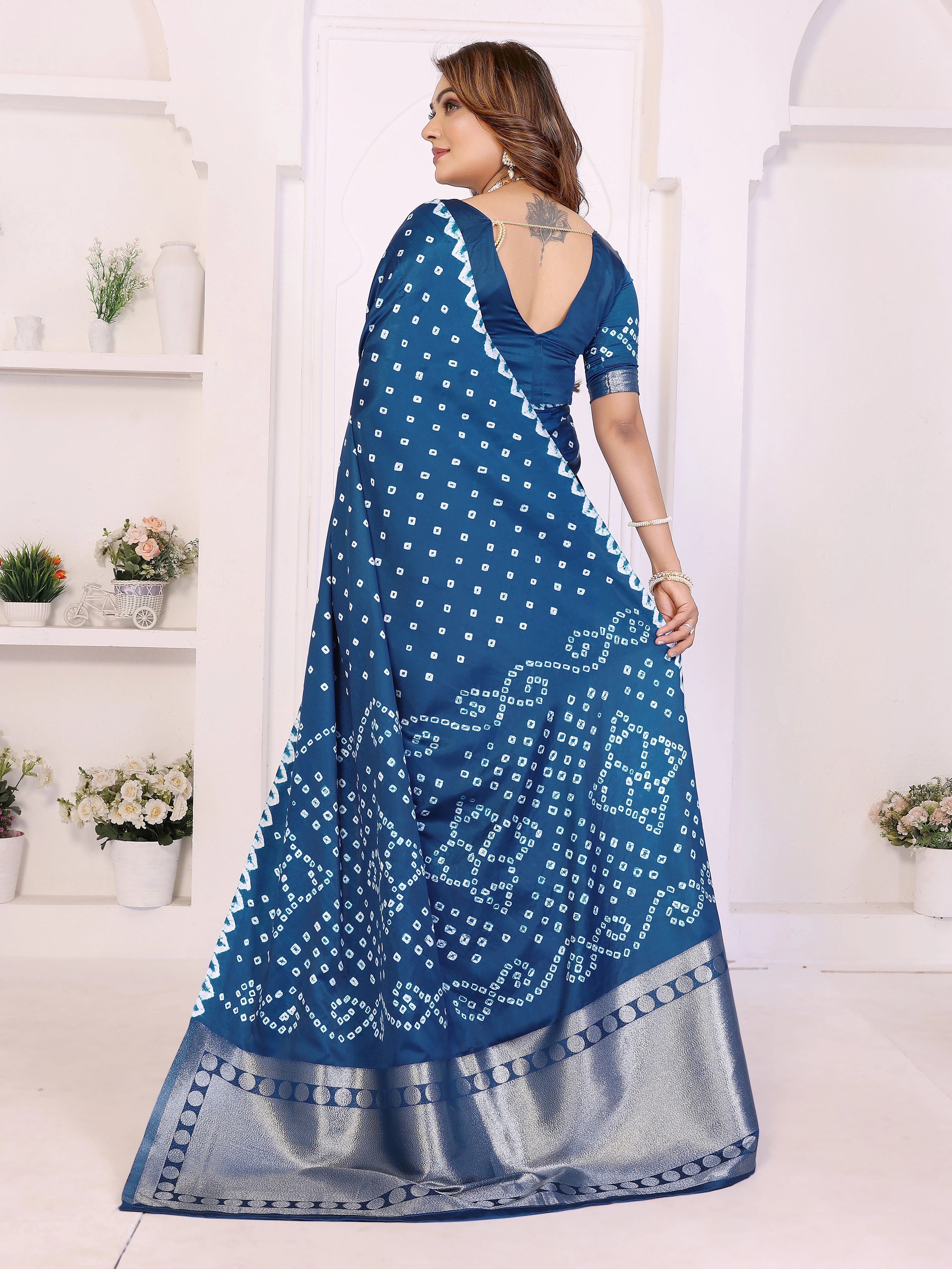Woman wearing a blue saree with white patterns in a white room.