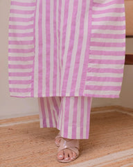 Person wearing pink and white striped pants and a matching top on a wooden floor.