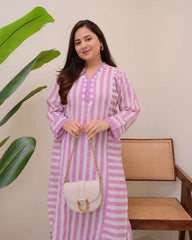 Woman in a pink and white striped dress holding a white handbag indoors.
