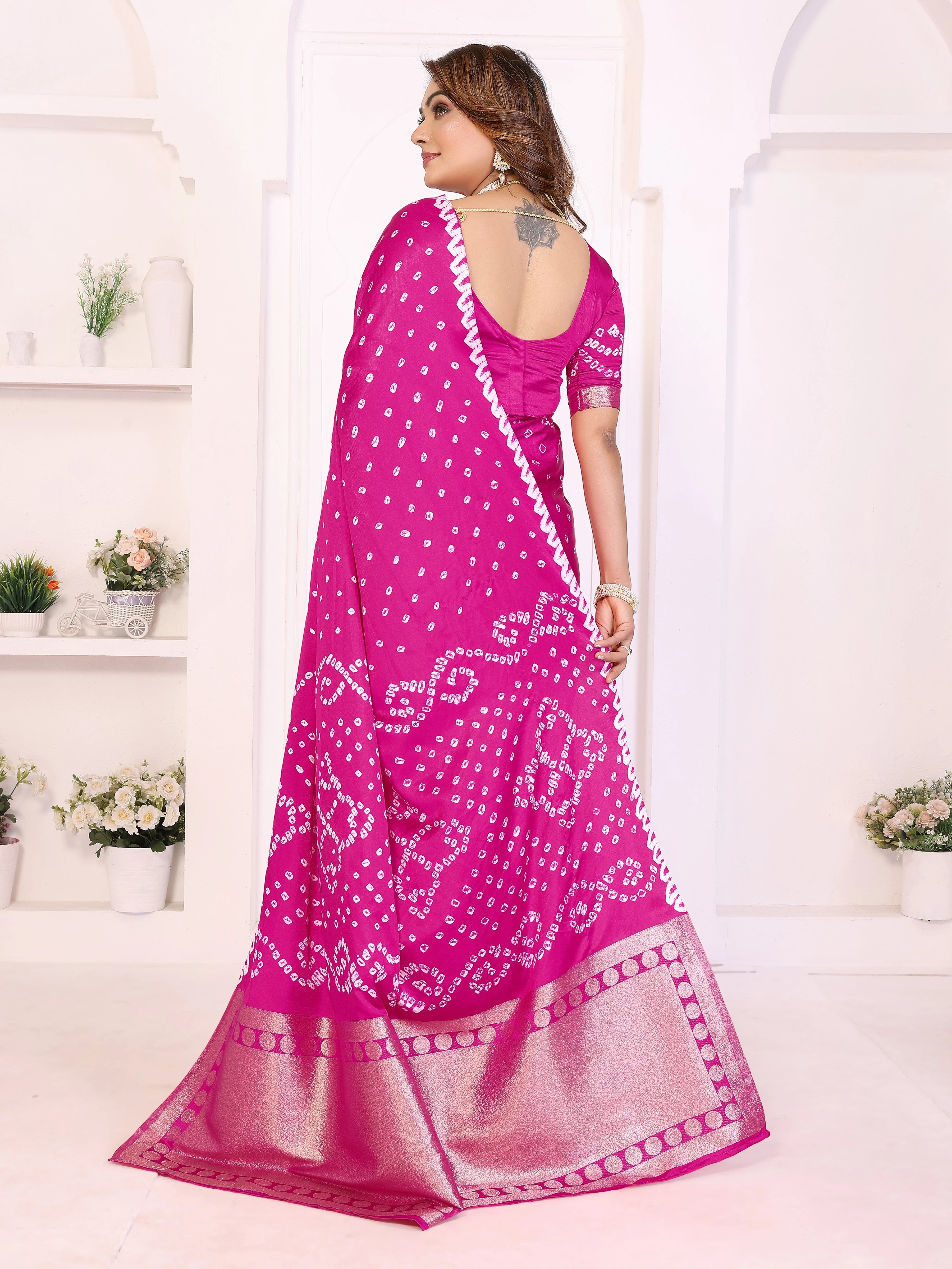 Woman wearing a pink saree with white patterns in a minimalistic setting