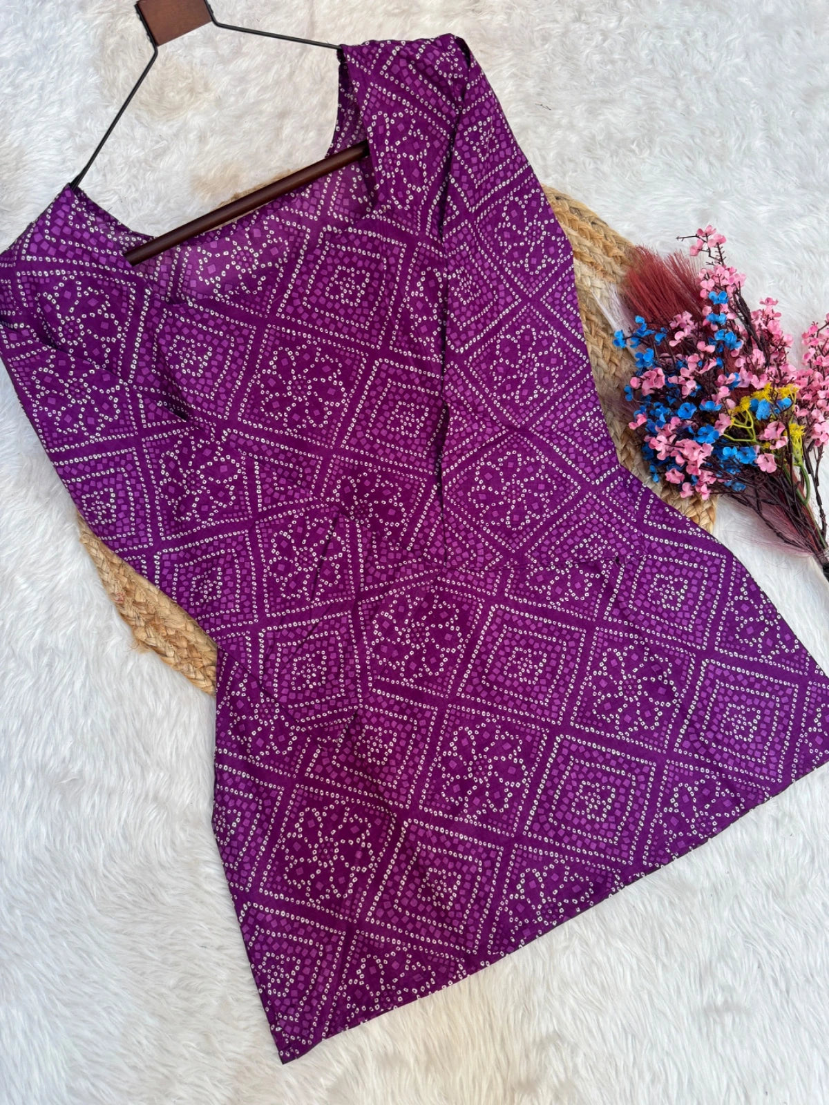 Purple patterned fabric on a hanger with flowers on a white background