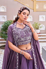 Woman in a traditional outfit with intricate designs, standing in an outdoor setting.