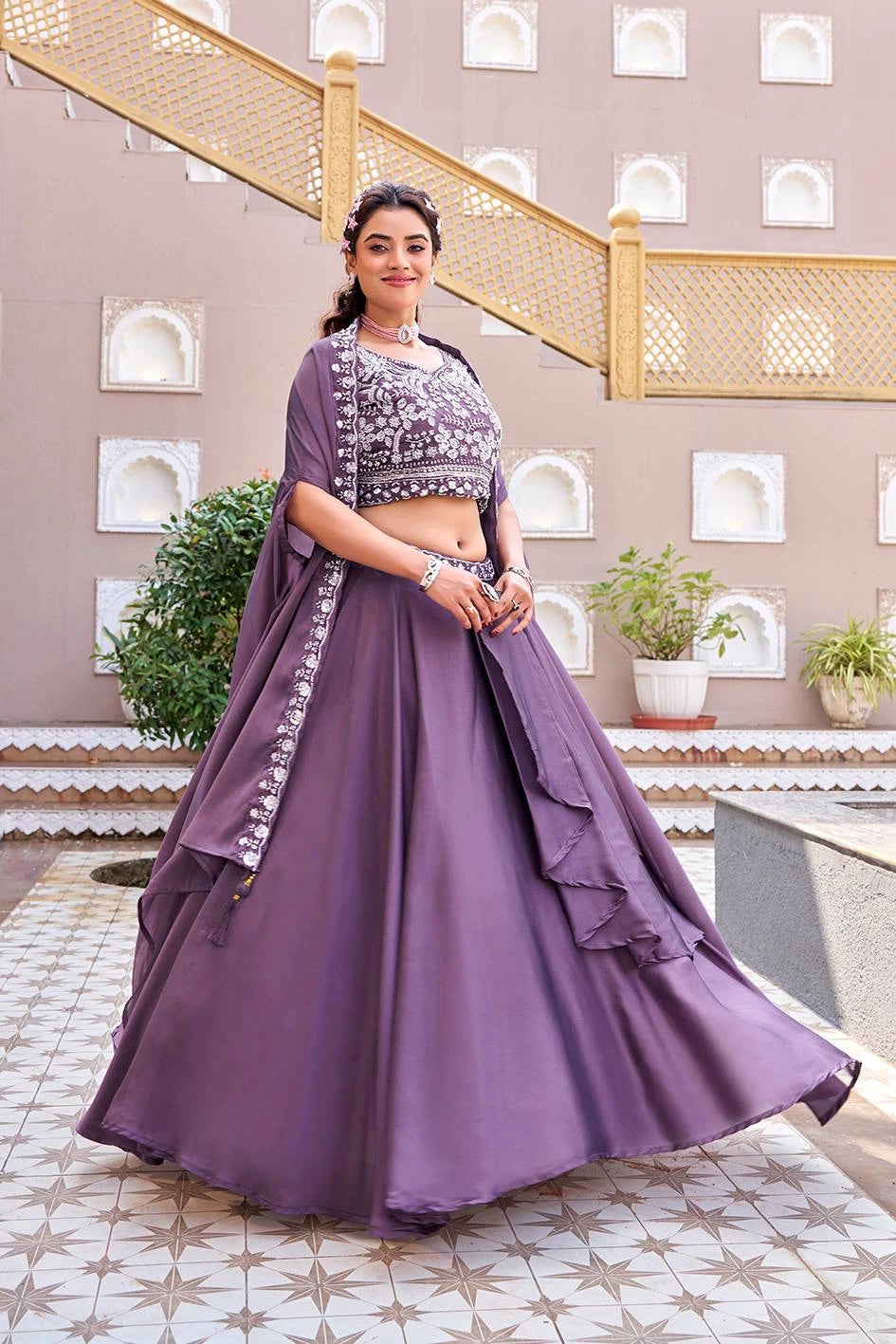 Woman in a purple traditional outfit standing in a decorative indoor setting.