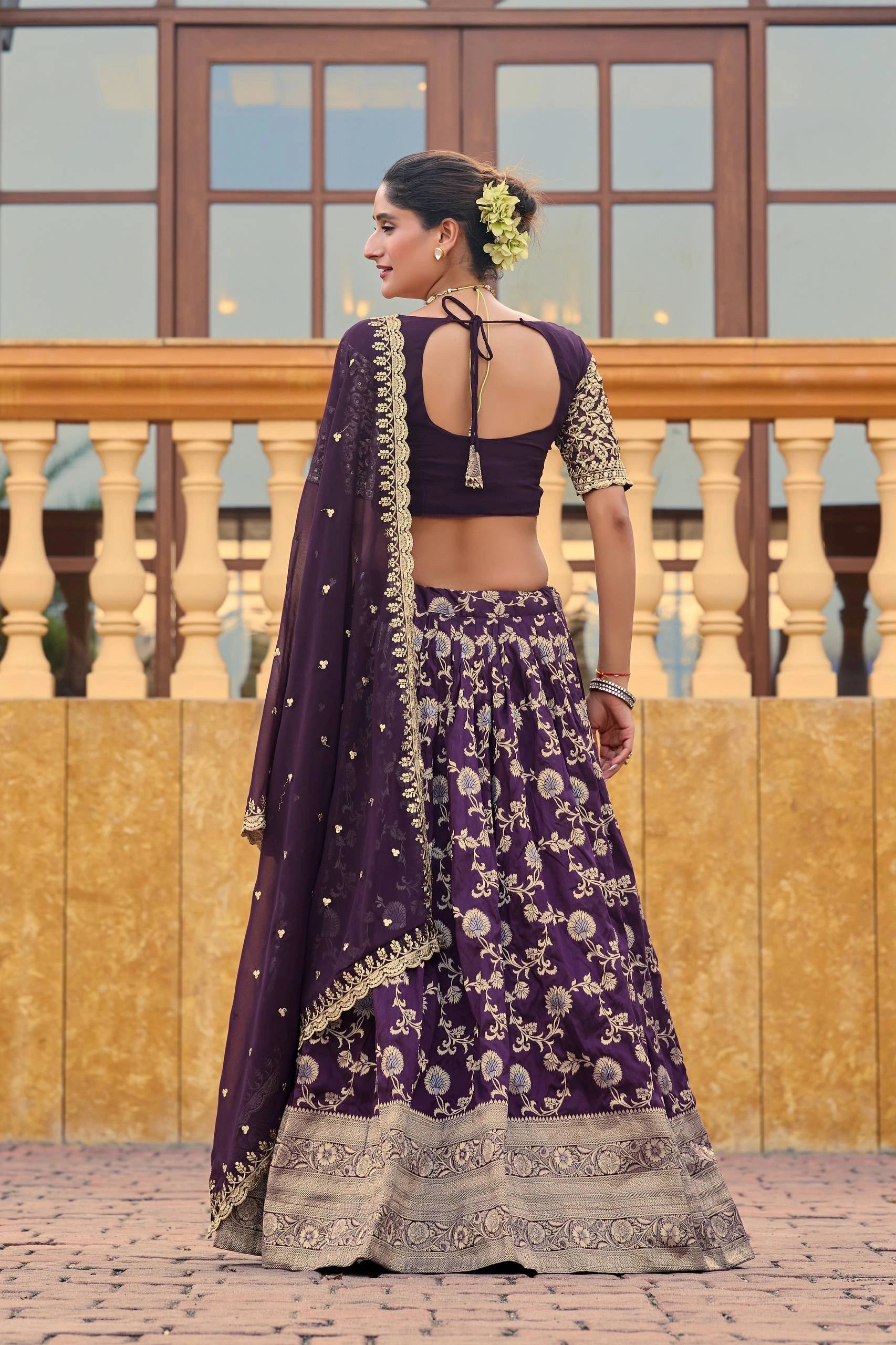 Woman in a purple traditional outfit with floral patterns standing on a wooden deck.