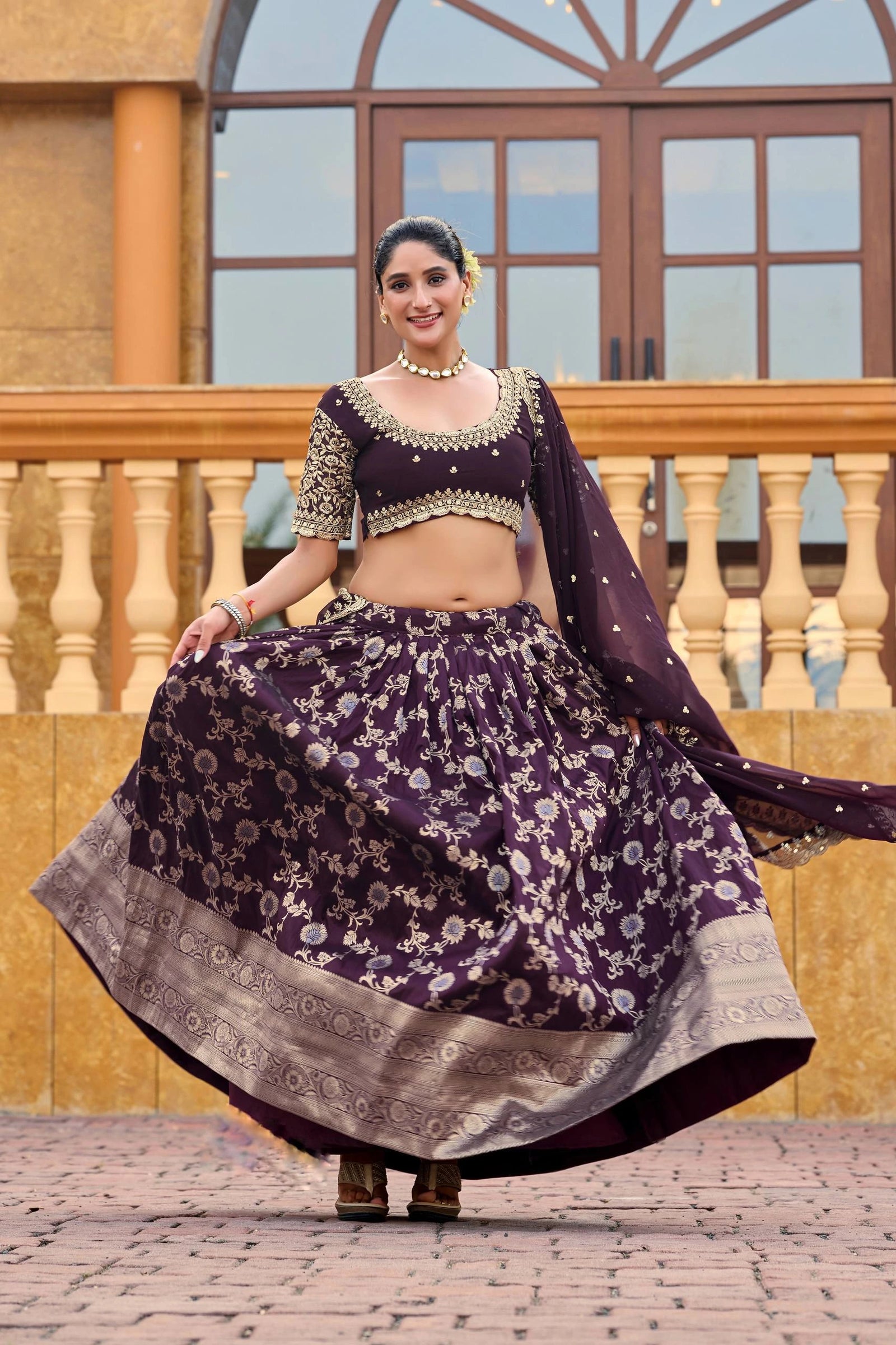 Woman in a traditional purple and gold outfit standing outdoors.