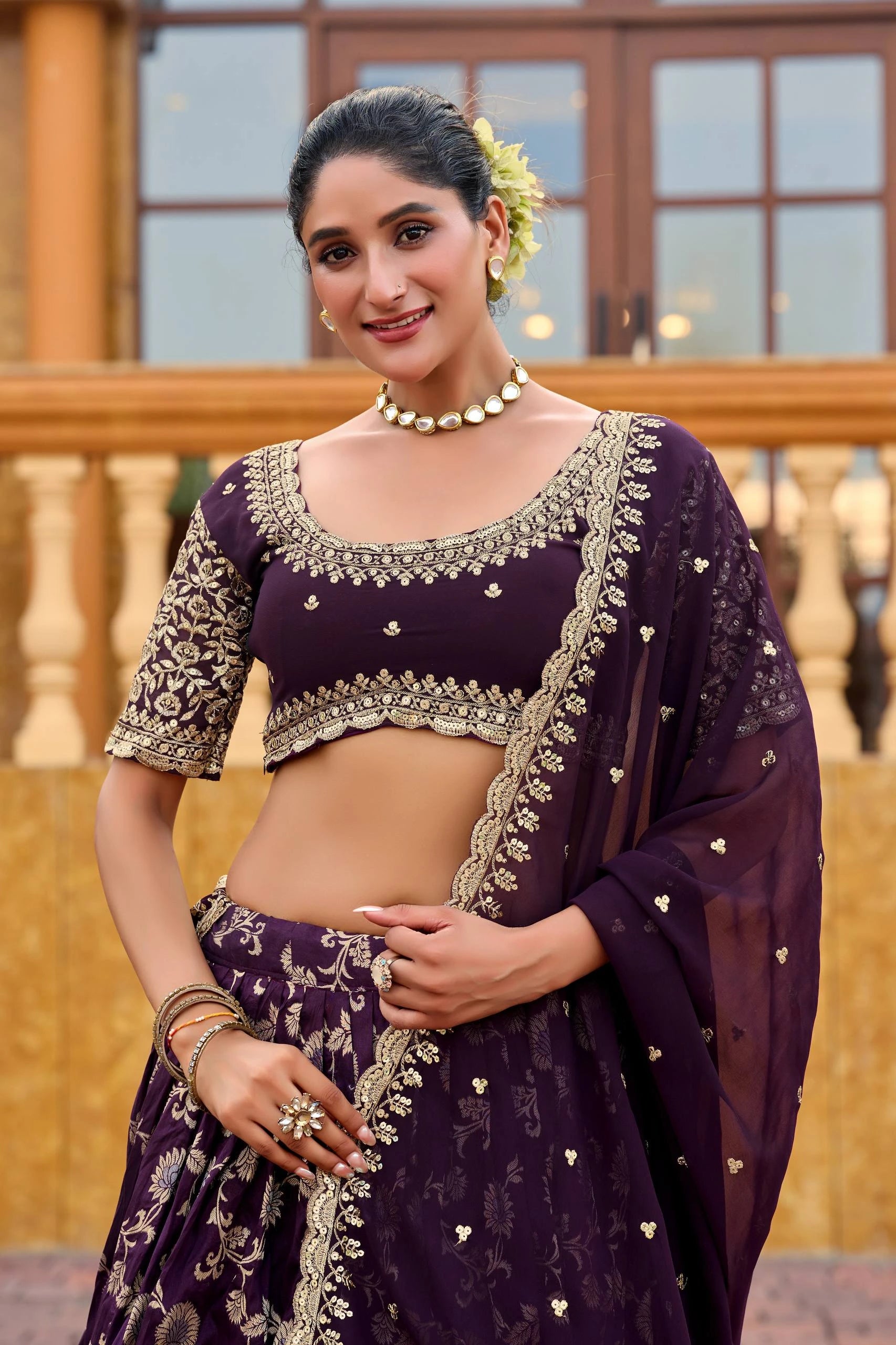 Woman wearing a traditional purple outfit with intricate designs outdoors.