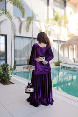 Woman in a purple traditional outfit standing by a pool with modern building in the background