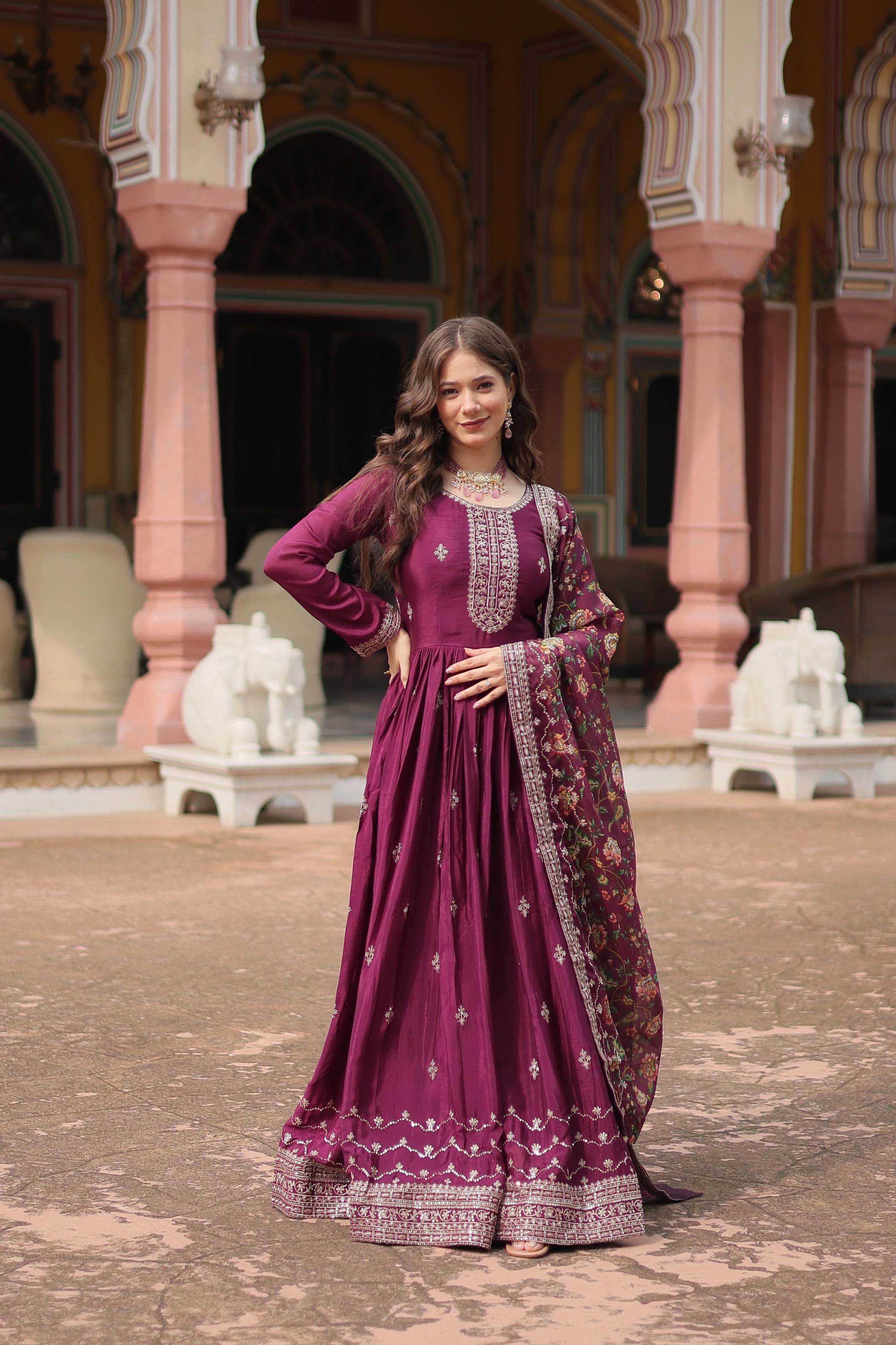 Woman in a purple traditional outfit standing in an ornate outdoor setting.