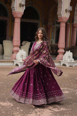 Woman in a traditional purple outfit with floral patterns standing in an ornate outdoor setting.