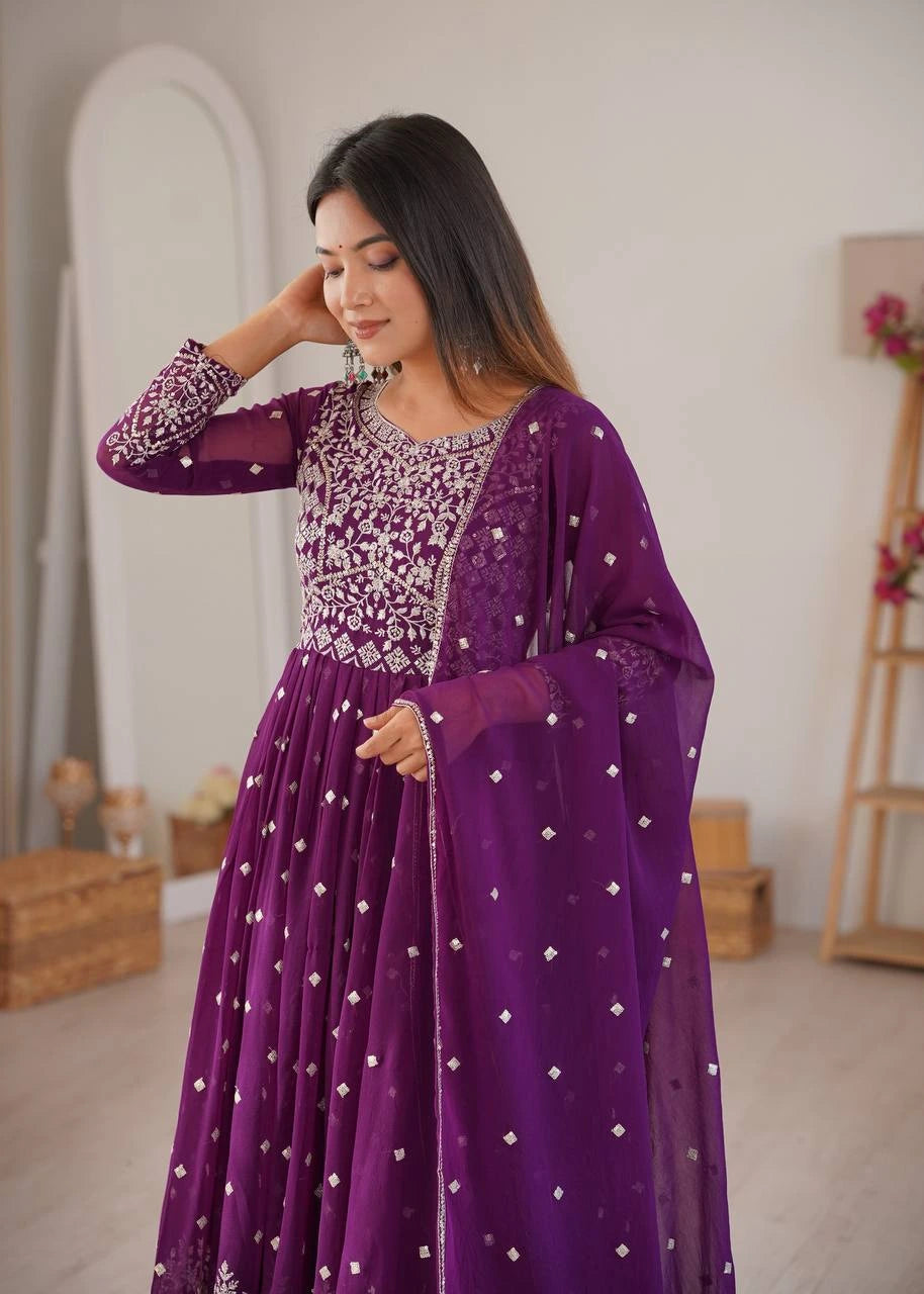 Woman wearing a purple traditional outfit with intricate designs indoors.