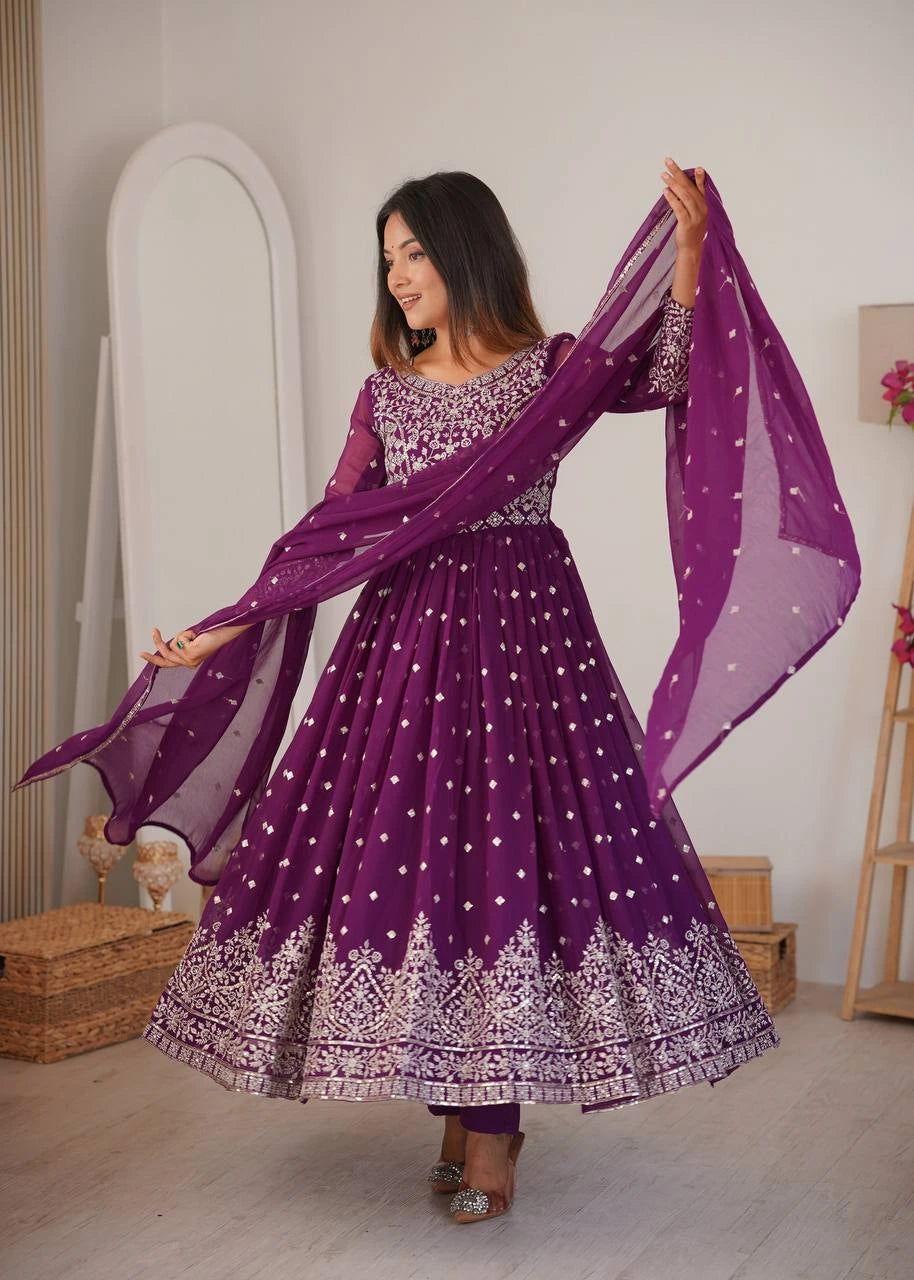 Woman in a purple traditional outfit with a matching dupatta in a room.