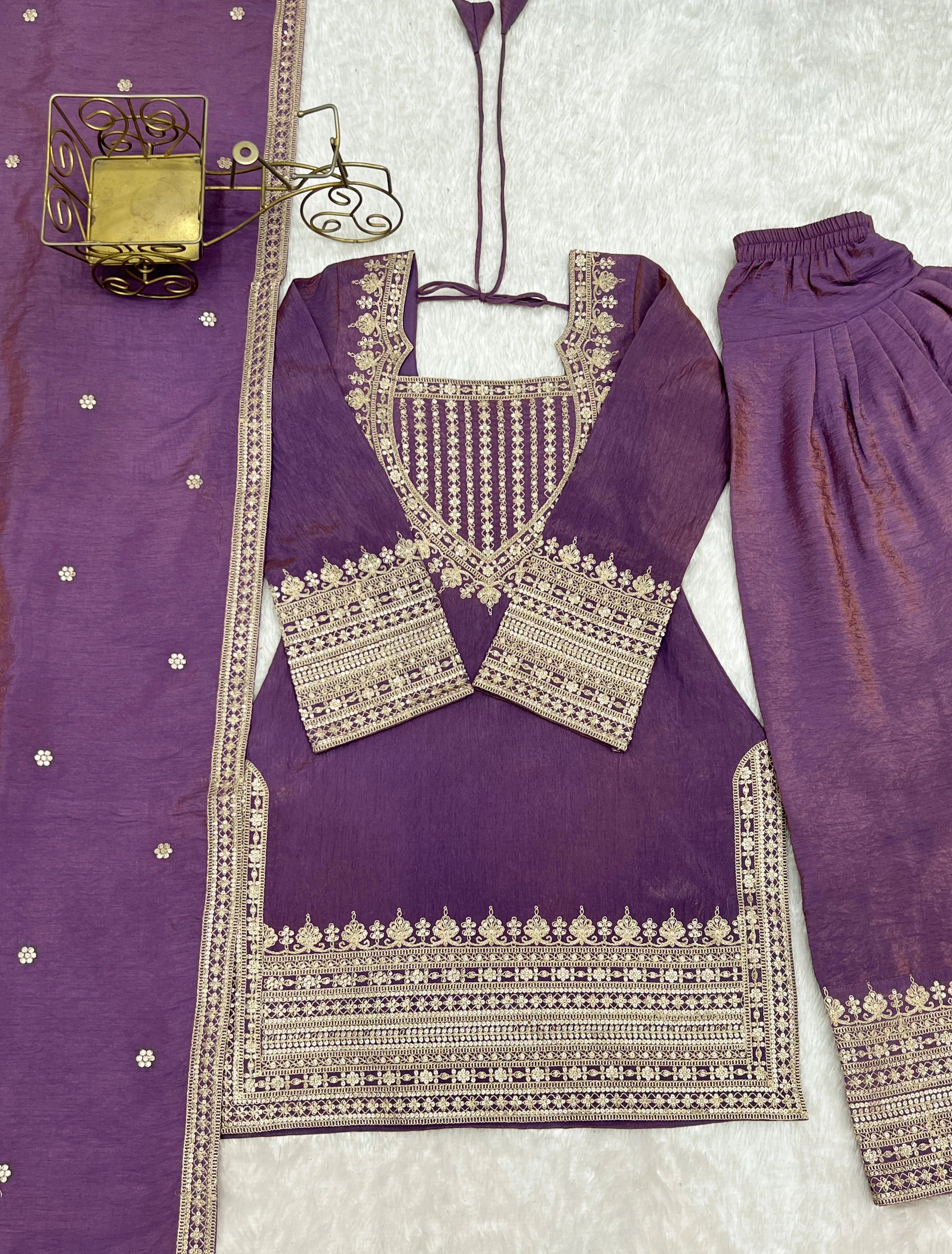 Purple traditional outfit with intricate silver embroidery on a light gray background