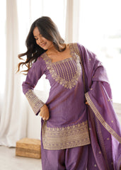 Woman wearing a purple traditional outfit with gold embroidery indoors.