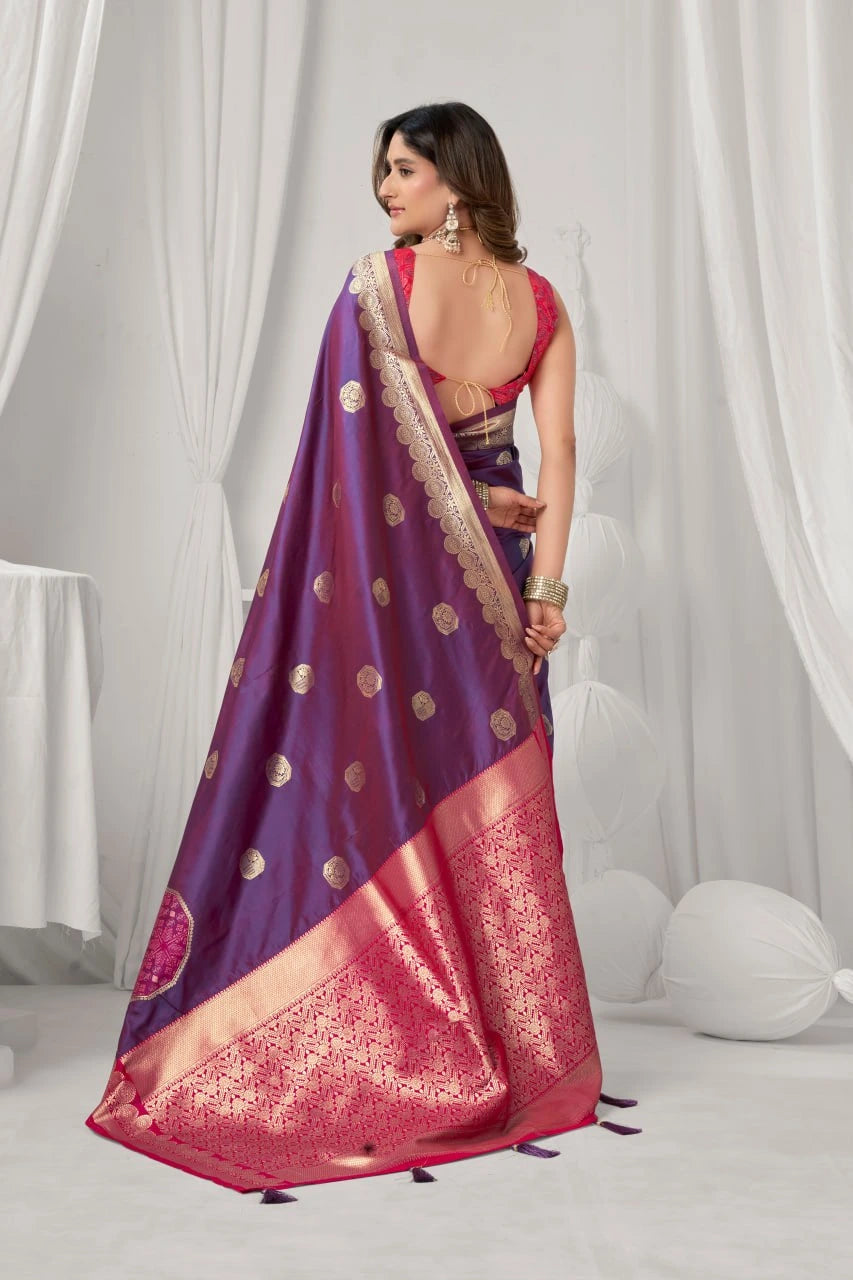 Woman wearing a purple and pink saree with a white curtain background