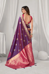 Woman wearing a purple and pink saree with a white curtain background
