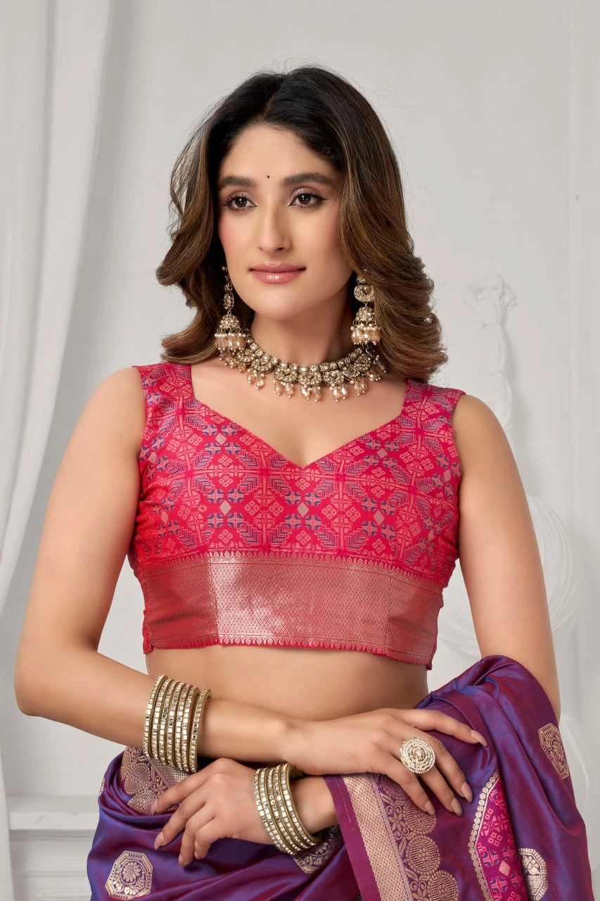 Woman wearing a red blouse and purple saree with jewelry against a white background
