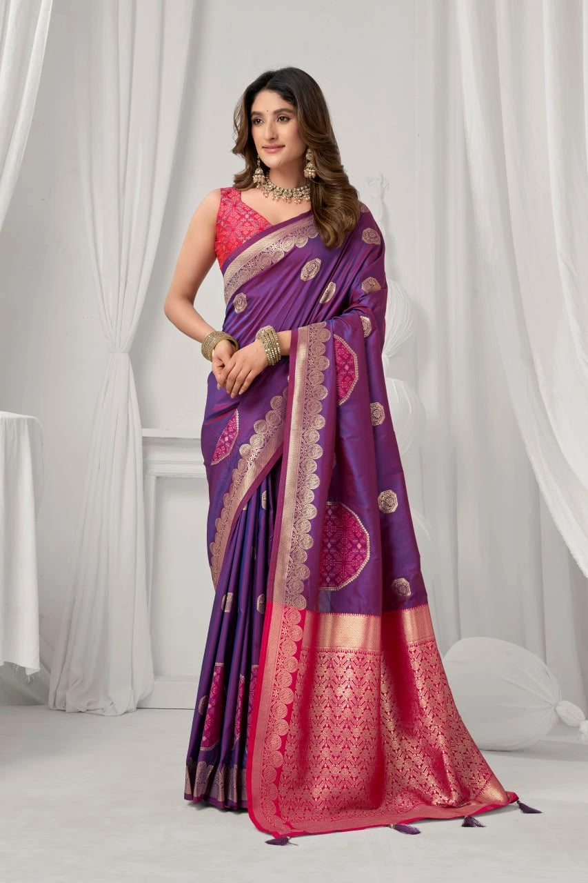 Woman wearing a purple and pink saree with a white curtain background