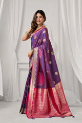 Woman wearing a purple and pink saree with a white curtain background