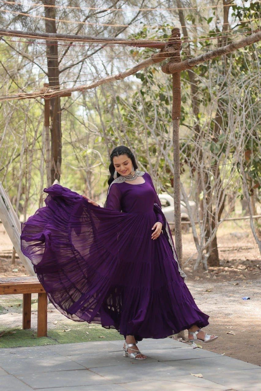 Woman in a purple dress standing outdoors with trees in the background