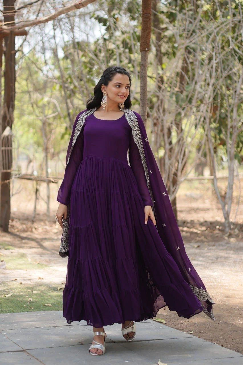 Woman in a purple dress with silver embroidery standing outdoors.