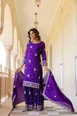 Woman in a purple traditional outfit standing in an elegant hallway.