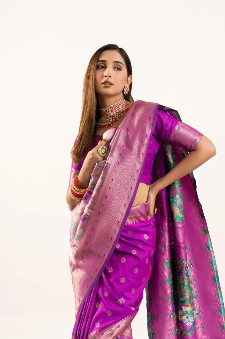 Woman wearing a vibrant purple saree with a white blouse on a white background