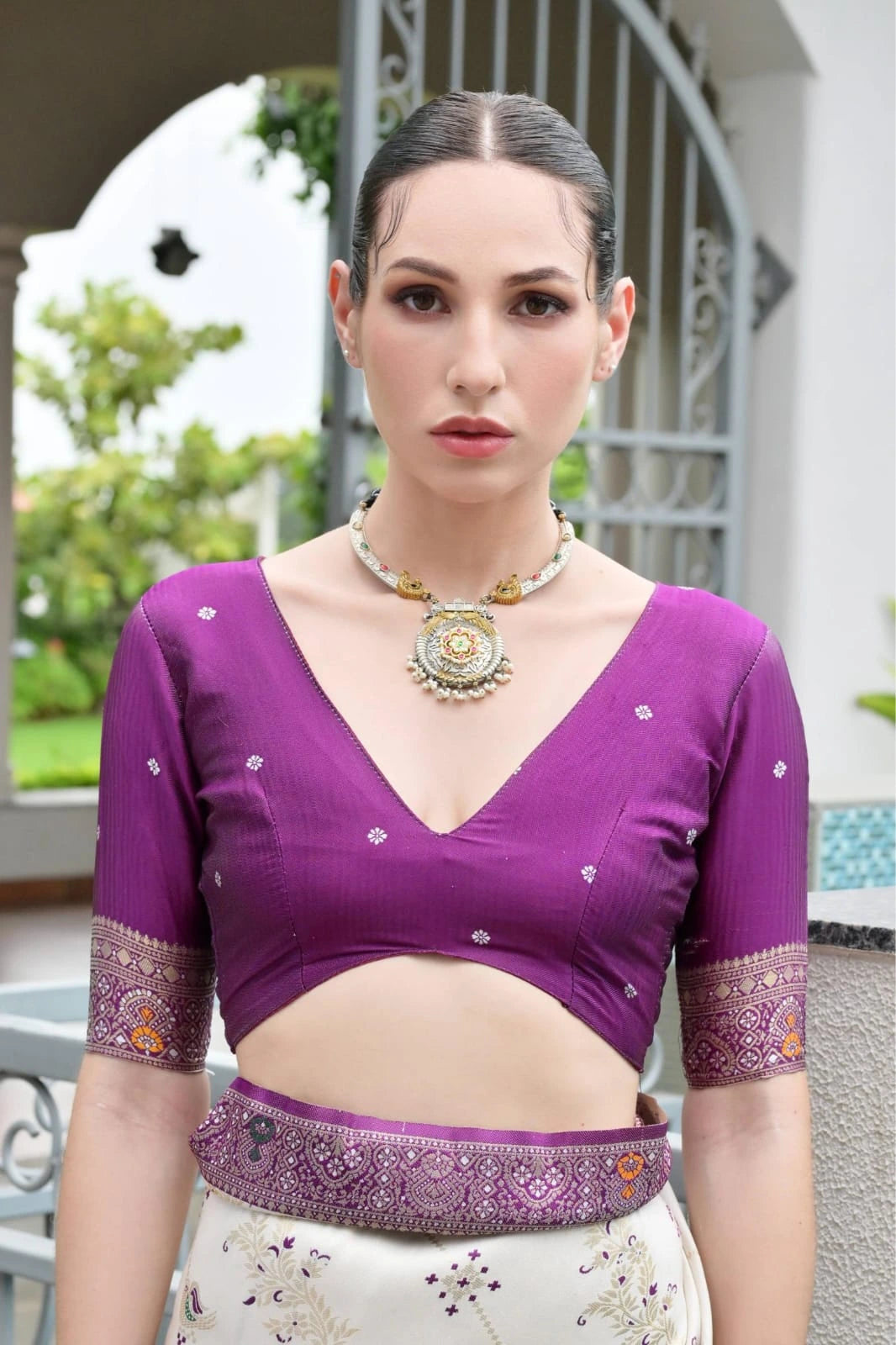 Traditional Banarasi silk saree in deep purple with ornate zari patterns draped gracefully.