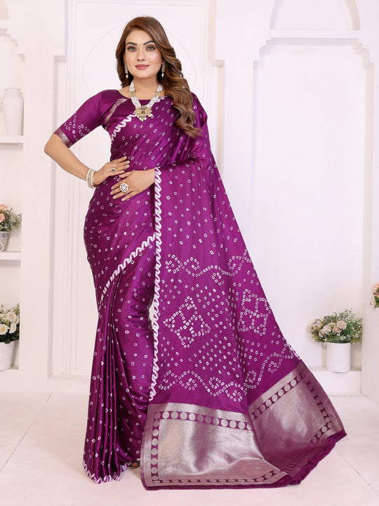 Woman wearing a purple saree with white patterns in a white room.