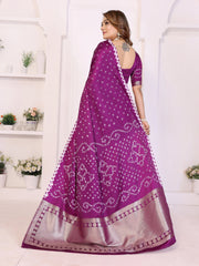 Woman wearing a purple saree with white patterns in a white room.