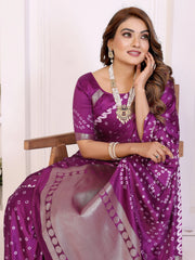 Woman in a purple saree with white patterns sitting on a chair.