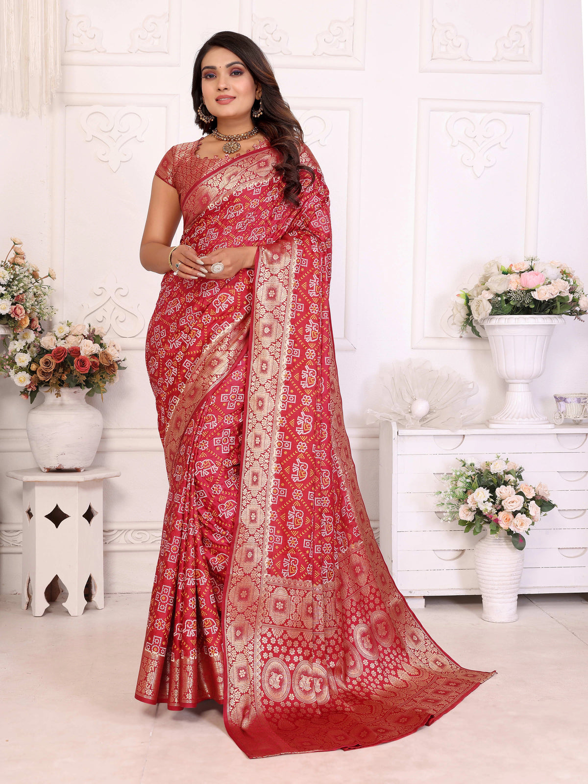 Woman wearing a red saree with white patterns in a decorated room.