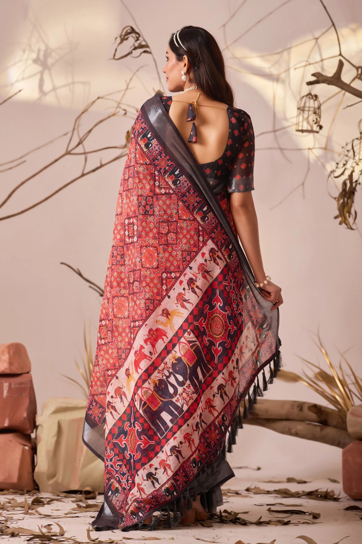 Woman wearing a traditional saree with intricate patterns in a decorative setting.