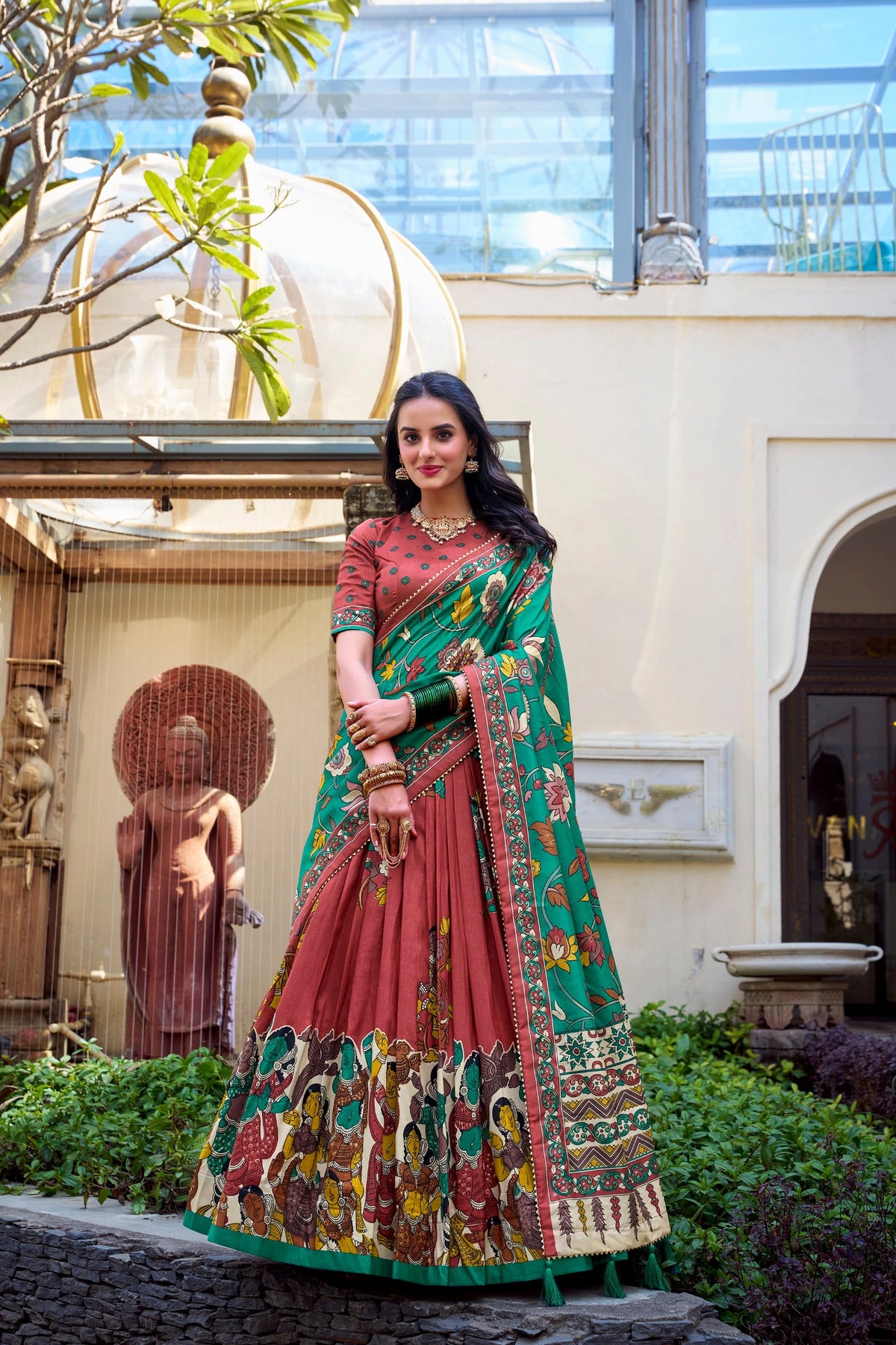 Stylish maroon Kalamkari printed saree with vibrant green border, cultural motifs, and graceful traditional design.