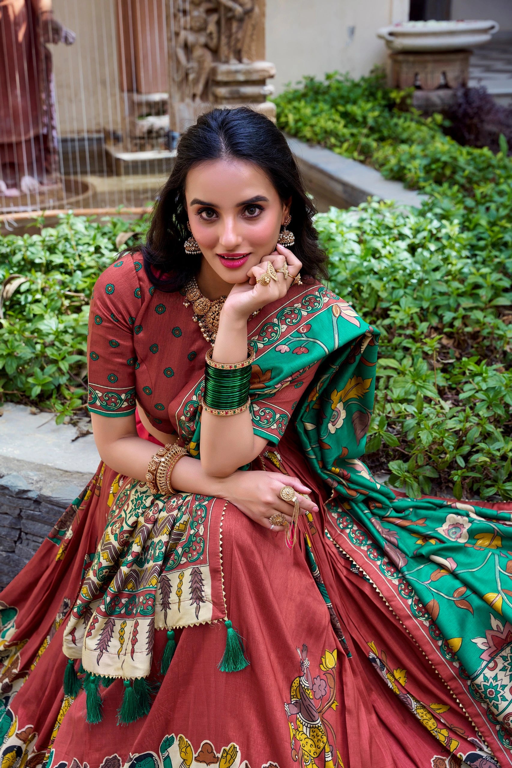 Elegant maroon Kalamkari printed saree with emerald green floral pallu and artistic traditional border.