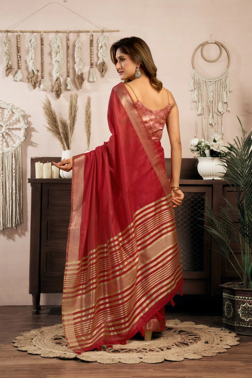 Woman in a red saree standing in a room with decorative elements.