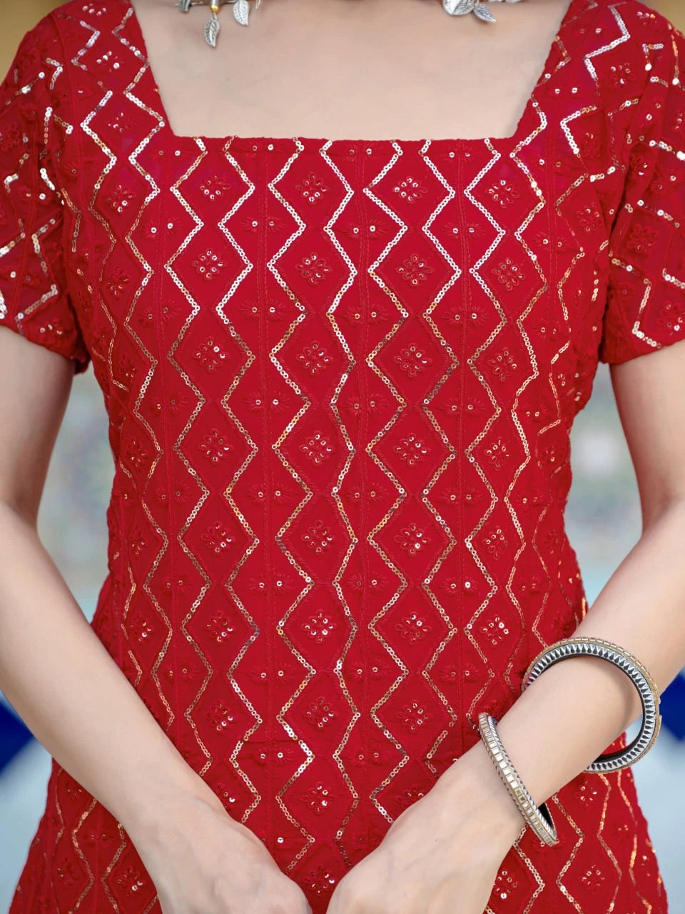 Red patterned dress with a person wearing it, focusing on the upper body.