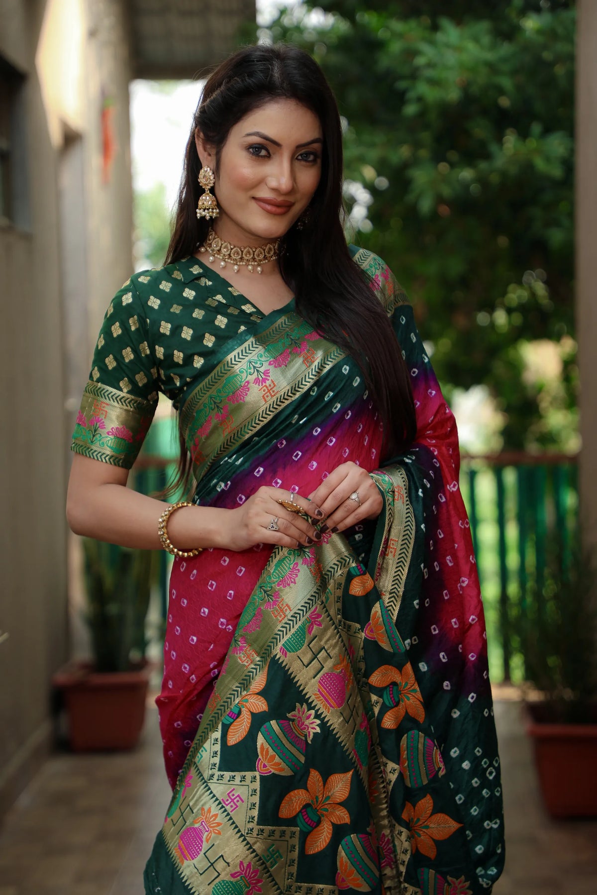 Woman wearing a traditional saree with a green and pink pattern, standing outdoors.