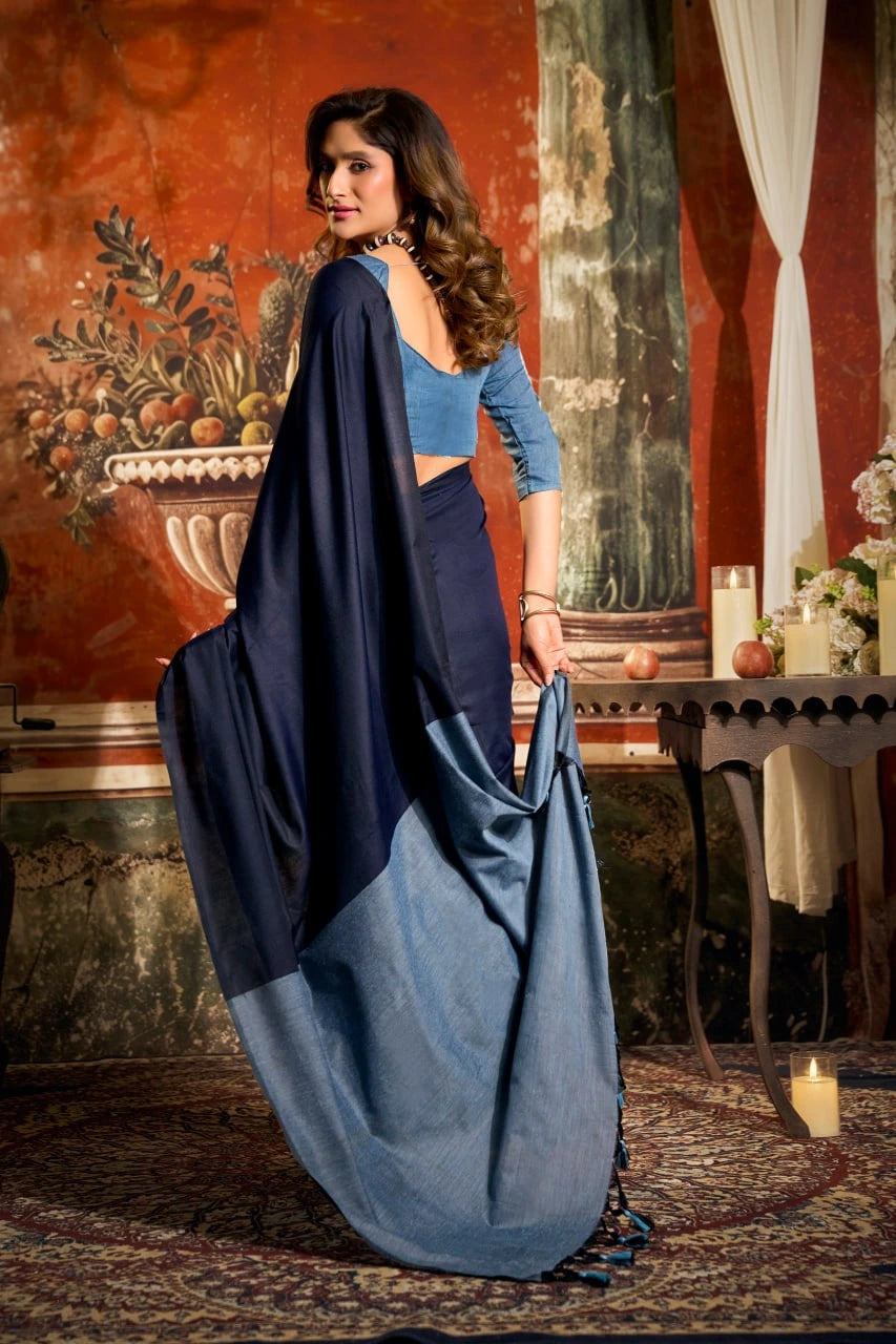 Woman holding a blue saree in an elegant room with decorative elements.