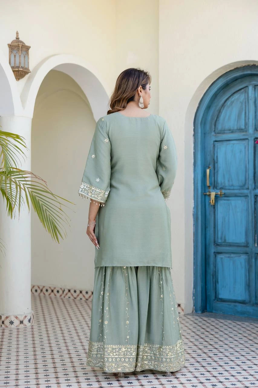 Woman in a light green traditional outfit standing in front of a blue door.