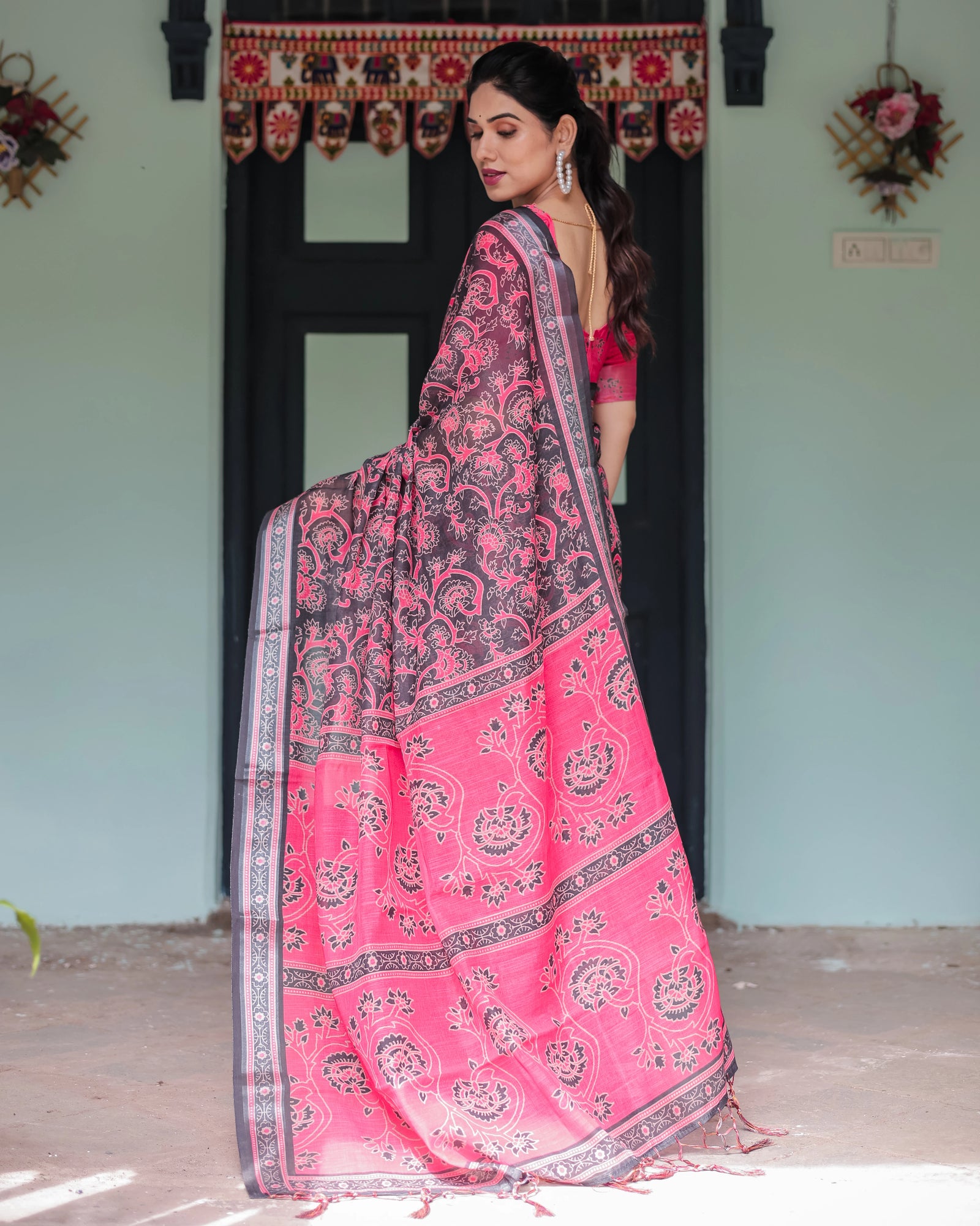 Woman wearing a pink and black saree in an indoor setting