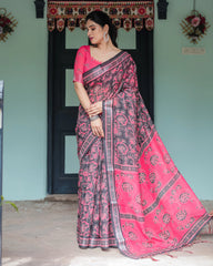 Woman wearing a pink and black saree in front of a door with decorative elements.