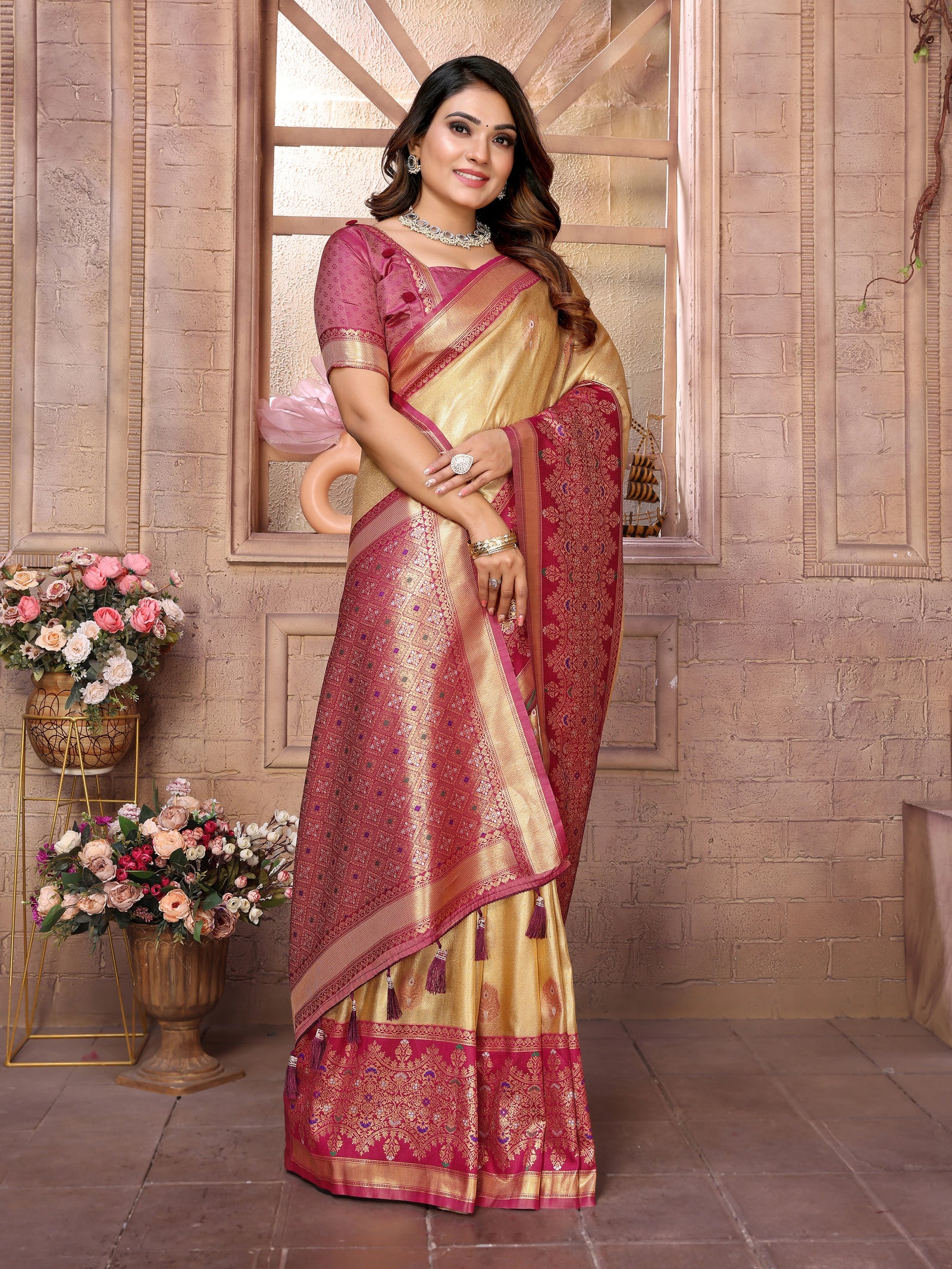 Woman in a traditional saree with intricate patterns against a decorative wall.