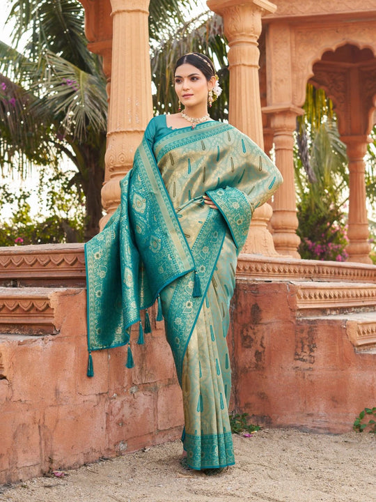 Woman in a teal saree standing in front of an architectural structure with columns.
