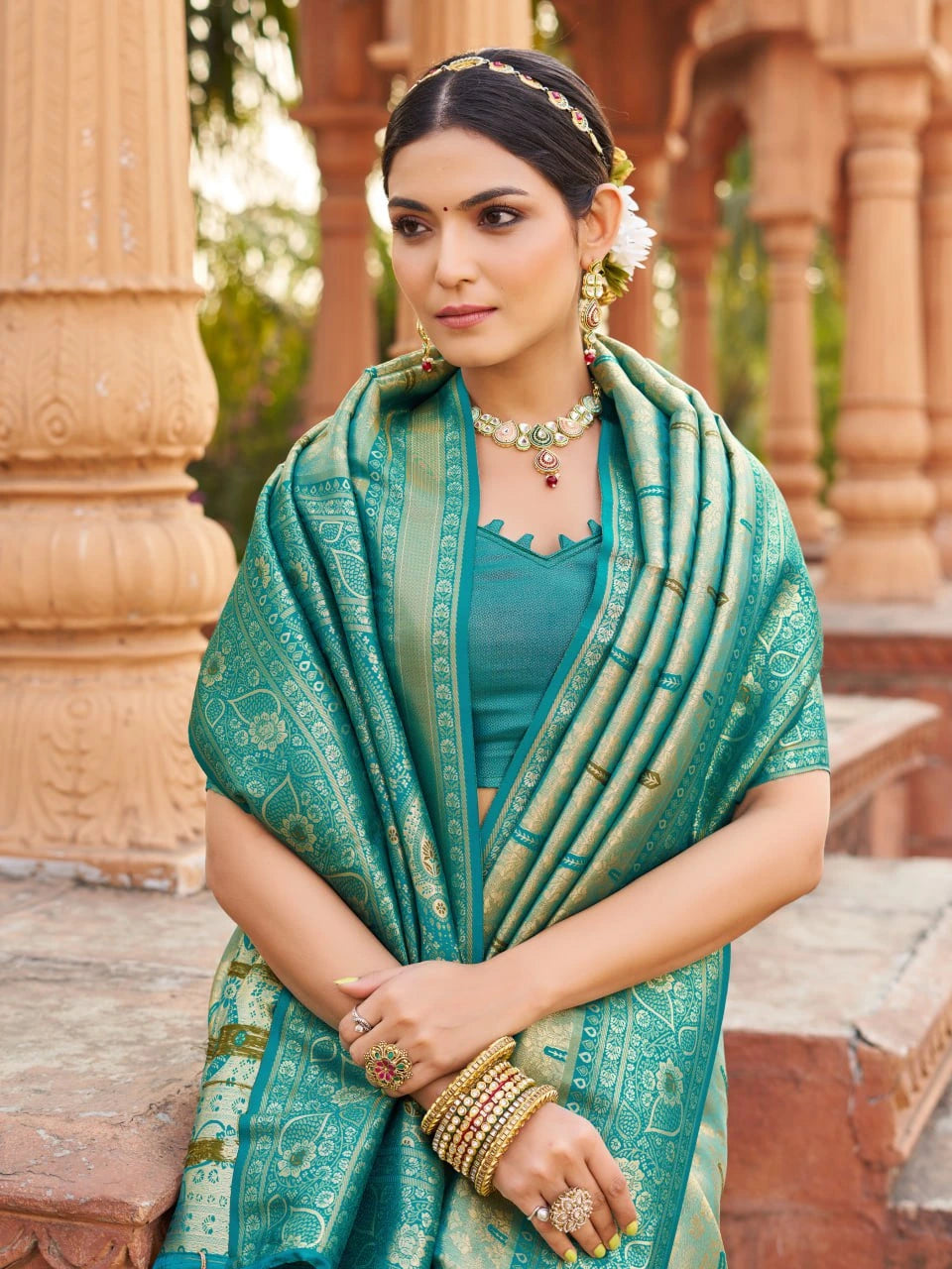 Woman in traditional attire with a green saree in an outdoor setting