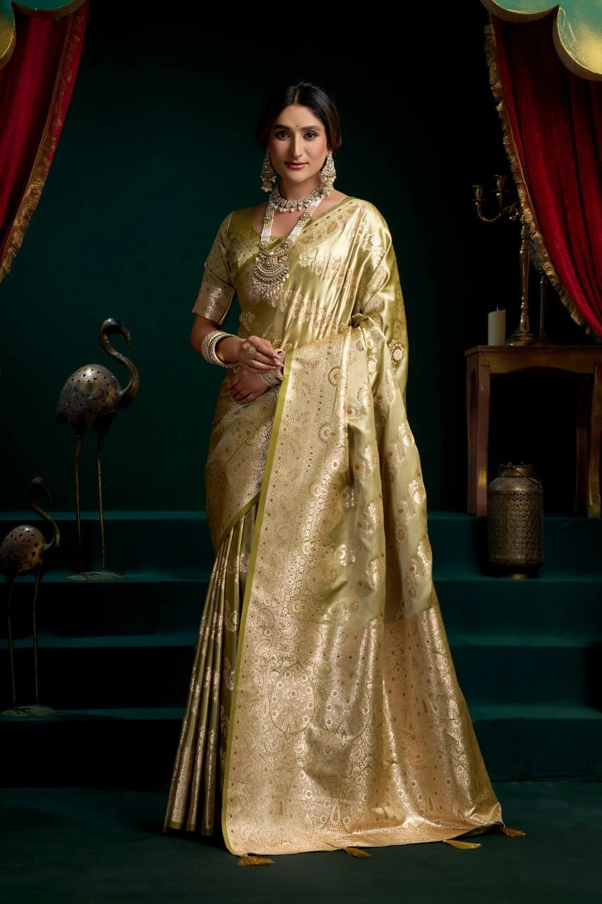 Woman in a gold saree standing in a decorative setting with red curtains and green walls.